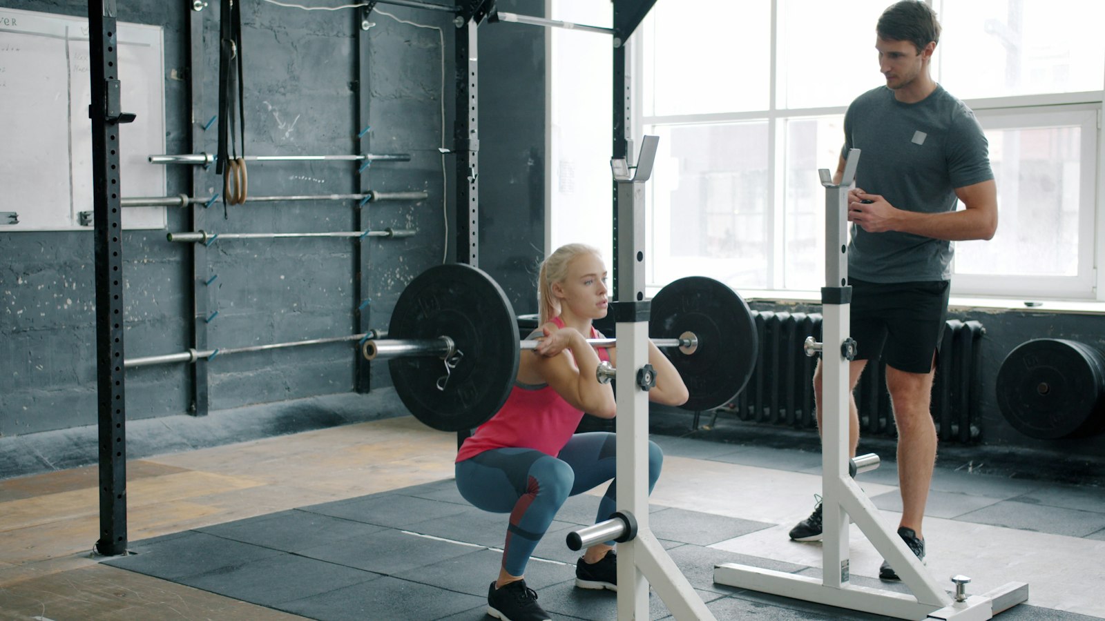 Man in his fifties performing a barbell squat with a coach